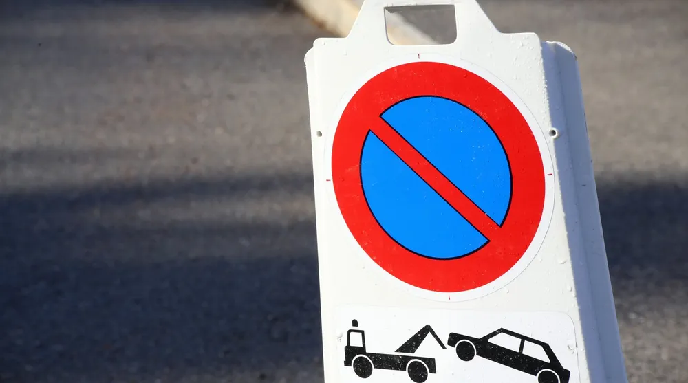 Panneau temporaire d'interdiction de stationner avec pictogramme d'enlèvement, posé sur la chaussée